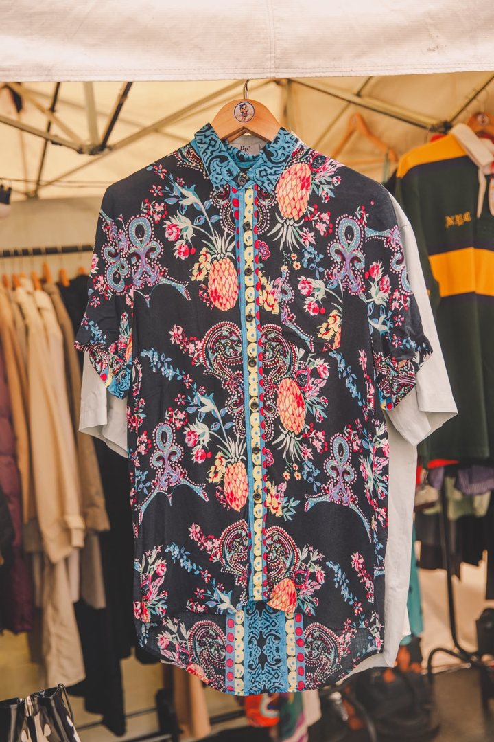 Camisa estampada de abacaxis e flores pendurada num cabide da arara